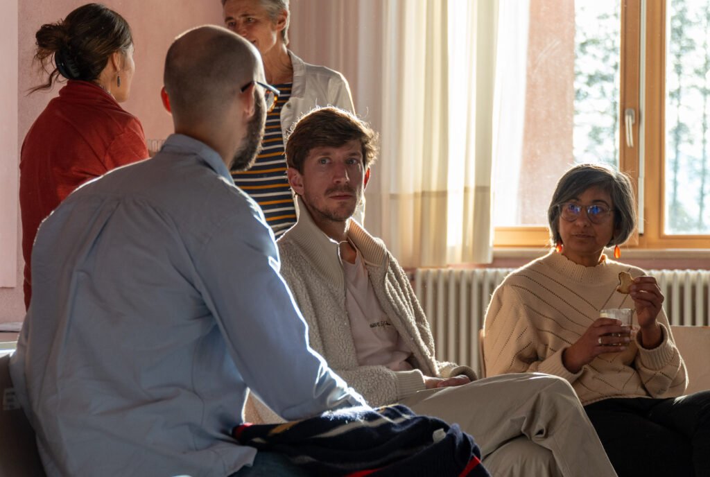 In the picture there are some people sitting , some people standing. They are engaged in a conversation.