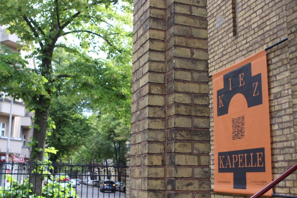 This is a close-up picture from outside the place with it´s name on a banner: “Kiezkapelle” which translates to neighborhood chapel. 