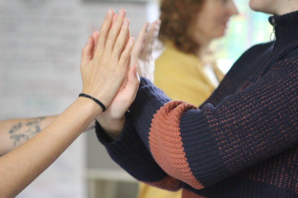 The picture shows the hands of two people physically conntecting by putting their palms together. 
